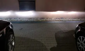 Jasne światła z przodu Audi A4 B6 oświetlają ścianę.