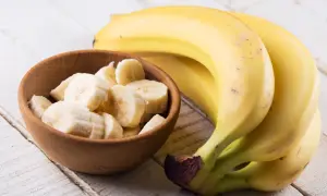 Kawałek banana w drewnianej miseczce obok całych bananów. Poznaj banan wartości odżywcze i ciesz się zdrową przekąską.