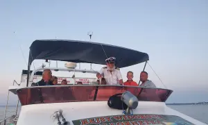 Kapitan z lornetką na pokładzie łodzi zaprasza na rejsy statkiem we Władysławowie. Rodzina cieszy się widokiem.