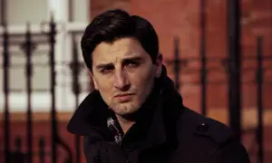 Een man met donker haar en een donkere jas kijkt peinzend voor zich uit. Waarom staren mensen? Misschien denkt hij na over het leven.