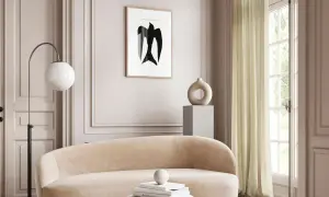 Ein stilvolles Wohnzimmer in greige farbe mit einem geschwungenen Sofa, einem modernen Lampenschirm und einem abstrakten Vogelbild.