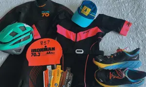 Triathlon gear laid out: wetsuit, helmet, swim cap, tri suit, running shoes, and energy gels. Everything you need to know what to wear for a triathlon.