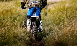 Motocyklista w stroju off-roadowym jedzie po trawiastym torze.