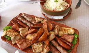 Talerz pełen mięsnych przysmaków: kiełbaski, grillowany kurczak, ziemniaki i sałatka z serem. Prawdziwe bałkany od kuchni!