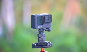 GoPro Hero 10 na statywie z czerwonym mocowaniem, na tle zieleni.