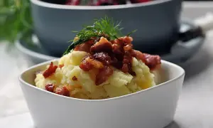 Pyszna zupa z botwiny z ziemniakami, podana z chrupiącym boczkiem i koperkiem.