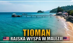 Malajska wyspa Tioman, z turkusową wodą, piaszczystą plażą i pomostem prowadzącym do lądu.