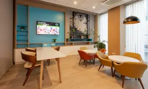 Wygodna strefa wypoczynkowa w hotelu B&B Łódź z kolorowymi fotelami i stołami, idealna na poranną kawę.