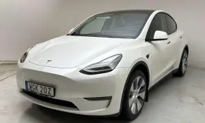 Vit Tesla Model Y, en begagnad elbil med mörk taklucka och stilrena fälgar. Perfekt för den miljömedvetna föraren.