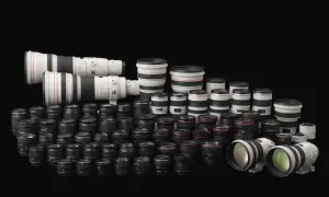 Vasta collezione di obiettivi per fotocamere, con diversi modelli e marche di macchine fotografiche, disposti su sfondo nero.
