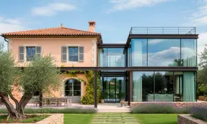Una casa tradicional con ampliaciones modernas de cristal y acero, rodeada de olivos y lavanda.