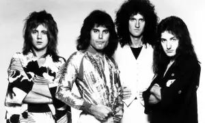 Czterech członków zespołu Queen, Freddie Mercury, Brian May, Roger Taylor i John Deacon, pozuje do zdjęcia. To oni tworzą zespół Queen, który nagrał największe hity.