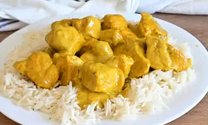 Piatto di riso basmati con saporito pollo al curry, ricoperto da una cremosa salsa gialla.