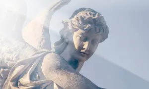 Kamienna rzeźba anioła, z promieniem światła padającym na twarz. W ciszy serca rodzi się modlitwa do anioła stróża o pomoc.