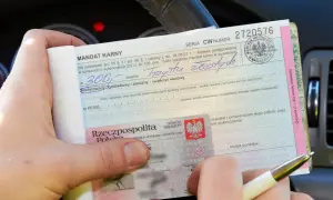 Mandat karny na 300 zł, z wpisanymi punktami karnymi 2025. Dokument jest wypełniany w samochodzie.
