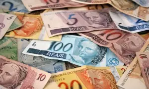 Stosy banknotów, w tym 100, 10 i 5 reali, stanowią walutę Brazylii.