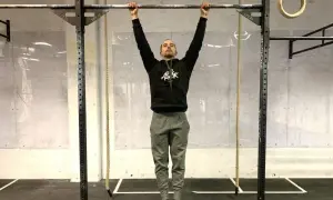 Un homme en tenue de sport s'accroche à une barre de traction, prêt à commencer son programme traction.