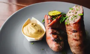 Zwei saftige, gegrillte Bratwürste mit Senf und Gurkenscheiben. Frische Bratwurst wie lange haltbar? Am besten sofort genießen!