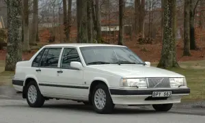 Vit Volvo 940 classic parkerad vid en skogsväg. Bilen är i fint skick med blank lack och kromade detaljer.