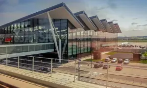 Nowoczesny budynek lotniska Gdynia z przeszkloną fasadą i samolotem na płycie lotniska.