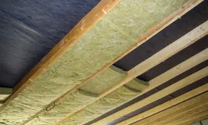Izolacja z wełny mineralnej ułożona między drewnianymi belkami, pod czarną membraną. Czy wełna może dotykać membrany? Tak, jeśli jest to odpowiednia membrana.