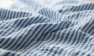 Blau-weißer Seersucker-Stoff mit charakteristischen Falten. Dieses Gewebe ist leicht und luftig, perfekt für Sommerkleidung.