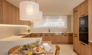 Cocina moderna con gabinetes de madera clara, encimeras blancas y una isla. Perfecta para tus ideas de cocinas.