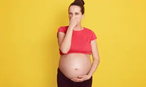 Kobieta w ciąży zatyka nos, cierpiąc z powodu śmierdzących gazów.