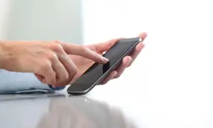 Dłonie trzymające smartfon, pokazujące jak doładować telefon w Play na kartę.