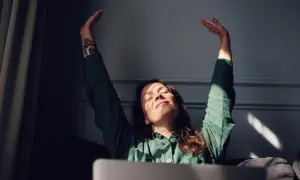 Vrouw met gesloten ogen en armen omhoog, genietend van zonlicht. Ze voelt zich eindelijk comfortabel in haar lichaam, na lang onzeker te zijn geweest.