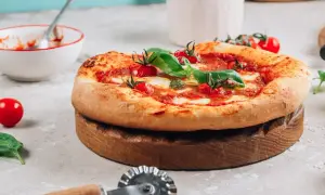 Pyszna pizza na drewnianej desce, gotowa do pokrojenia. Idealna do piekarnika, dzięki kamieniowi do pizzy.