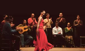 Una vibrante artista flamenco, con un vestido rojo, baila apasionadamente mientras músicos la acompañan.
