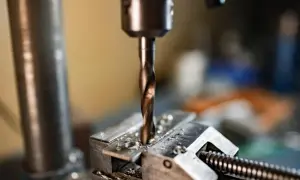 Wiertło wkręca się w metalowy element zamocowany w imadle.