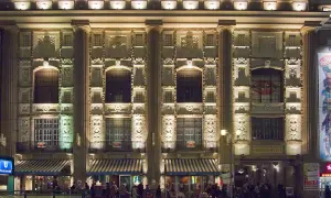 Der Admiralspalast Berlin bei Nacht, beleuchtet mit Säulen und Verzierungen. Menschen stehen vor den Eingängen und Cafés.