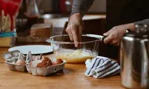 Préparation d'une crème pâtissière façon Cyril Lignac : des œufs battus dans un bol, des coquilles d'œufs à côté.