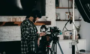 Operator z słuchawkami ustawia profesjonalną kamerę, gotową do nagrania wideo w wysokiej jakości, wykorzystując potencjał kodeka h265.