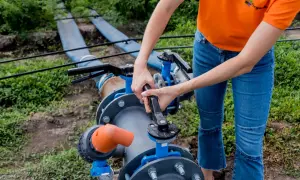 Montaż pompy głębinowej w studni kręgowej. Ręce dokręcają zawór przy systemie nawadniania.