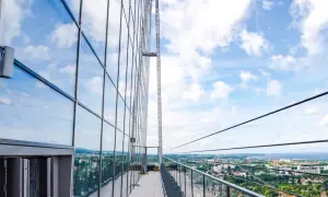 Widok z tarasu widokowego Olivia Star na miasto i morze. Szklana fasada odbija błękitne niebo z chmurami.