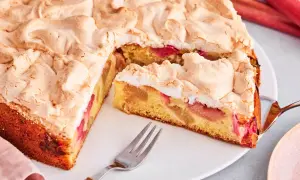 Saftiger Rhabarberkuchen mit luftigem Baiser, ein Stück ist schon angeschnitten.