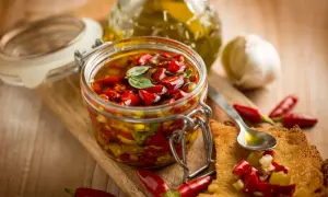 Peperoncino sott'olio con aglio, un tesoro piccante in un barattolo di vetro, pronto per insaporire ogni piatto.