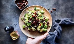 Frischer Brokkoli Salat mit Nüssen und roten Zwiebeln auf einem Holzteller, bereit zum Genießen.