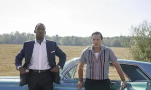 Obsada filmu Green Book: Mahershala Ali w eleganckim garniturze i Viggo Mortensen w koszuli z lat 60. stoją obok siebie przy samochodzie.