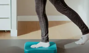 Exercice d'équilibre sur un coussin bleu pour améliorer la proprioception cheville.