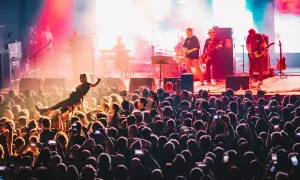 Energiczny koncert w klubie Stodoła Warszawa. Tłum szaleje, a na scenie gra zespół. Jedna z fanek jest niesiona przez publiczność.