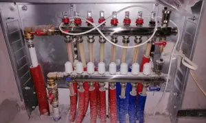 System ogrzewania podłogowego z rozdzielaczem. Widać tu m.in. ilu żyłowy kabel do termostatu pokojowego, zawory i rurki.