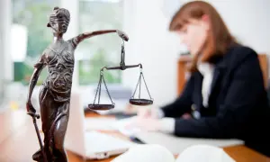 Statua della Giustizia con bilancia, avvocato al lavoro. Un successo per il ricorso invalidità civile vinto.