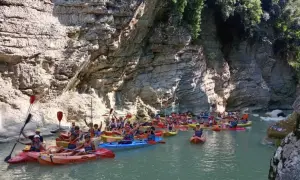 Gruppo in canoa esplora un canyon con pareti rocciose imponenti, navigando tra le marmitte dei giganti scavate dall'acqua.