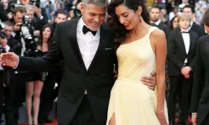 George und Amal Clooney auf dem roten Teppich, ein Beispiel für den Gala-Dinner-Dresscode: Er im Smoking, sie in einem eleganten gelben Kleid.