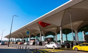 Nowoczesny terminal lotniska w Bodrum, z charakterystycznym dachem i ruchem samochodów.