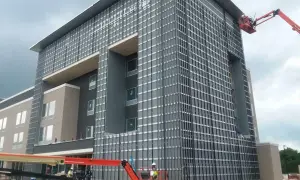 Instalación de sistemas de fachadas ventiladas en edificio moderno. Obreros en plataformas elevadoras trabajan en la colocación de paneles.